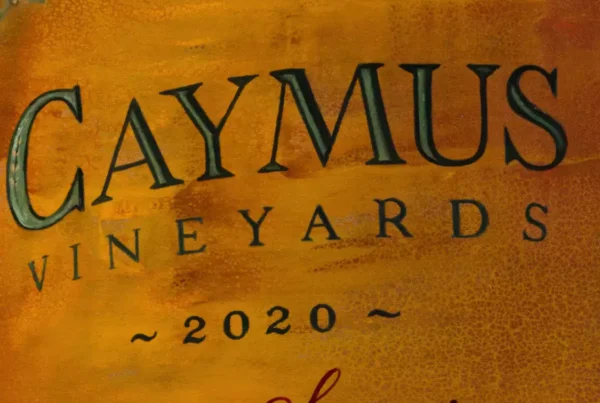Close-up of Caymus bottle label in 'A Perfect Moment' painting by Monica Marquez Gatica
