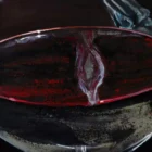 Close-up of the red wine swirling in the glass from "Evening Elegance," capturing the fluid movement and rich hues created through Monica Marquez Gatica's hybrid fluid realism technique.