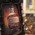 A black-framed cookie displaying a bottle of Blanton’s bourbon against a rich, red background.