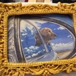 golden-framed cookie depicting a golden retriever smiling in an open field under a clear sky.