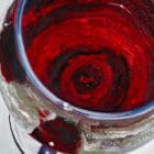 Close-up of crimson wine swirling in a glass with fine textures and light reflections.