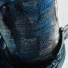 Close-up of textured wine bottle with deep blues and intricate detailing.