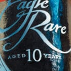 Close-up of the Eagle Rare logo and label on the painting "Spirit of the Soar," with intricate oil painting details over a textured acrylic pour