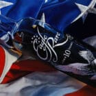 A hyper-realistic painting of an Eagle Rare 10-Year Bourbon bottle resting on an American flag, symbolizing tradition, craftsmanship, and the pursuit of excellence.